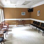 Spacious waiting room with neutral carpeting and rows of black chairs along the walls