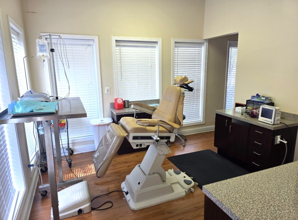 Specialized dental surgery room equipped with a modern white patient chair and overhead clinical monitors