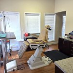 Specialized dental surgery room equipped with a modern white patient chair and overhead clinical monitors