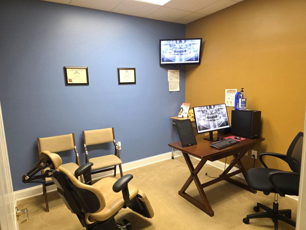 Consultation office with two patient chairs facing a desk with a computer monitor displaying dental X-rays